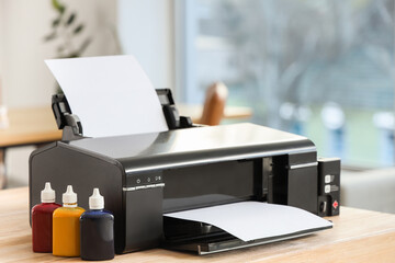 Modern printer with paper and ink on table in office