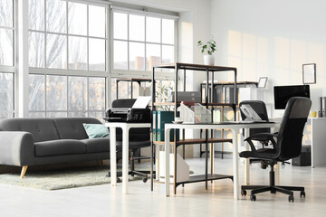 Interior of modern office with desks, sofa and printer