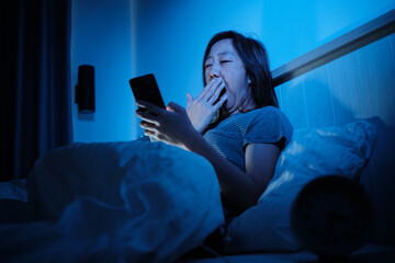Asian female single is sleepless, using mobile phone before sleep, browsing social media, chatting addiction, insomnia all night in bedroom, mature and menopausal woman, widow, middle-aged lifestyle.