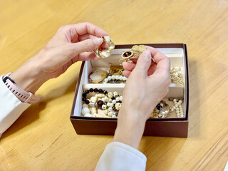 箱に入ったアクセサリーを持つ女性の手