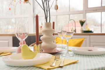 Easter table setting with candles and tree branches in kitchen, closeup