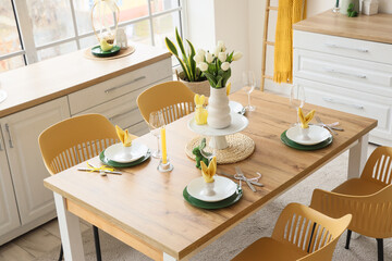 Dining table set for Easter with tulips in light kitchen