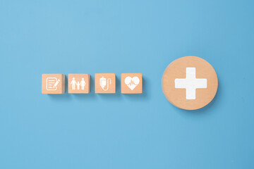 Concept of health insurance and medical. Wooden block with icons about health insurance and access to health care, health care planning on a blue background.