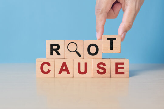 Root cause analysis concept. Define problems to find solution. Business problem solving. Hand holds the wooden cubes with text ROOT CAUSE and magnifying glass icon on grey background