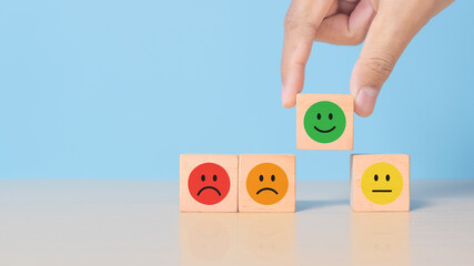Smiley face mental health assessment positive. Hand putting excellent emotion wood cube block, child wellness,world mental health day lifestyle of life concept.