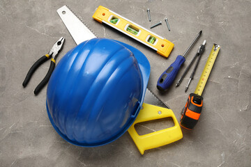 Fototapeta premium Hardhat and construction tools on grey grunge background
