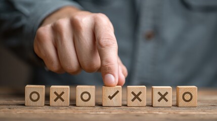 A hand placing a wooden block with a checkmark on a row of blocks with various symbols.