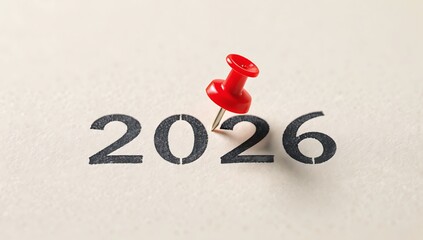 The year 2026 highlighted with a red pushpin on a surface. It represents the concept of future planning or a significant date