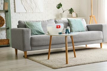 Modern inhalers, pills and first aid kit on coffee table in living room