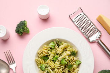 Plate of delicious fusilli pasta with broccoli and cheese on pink background