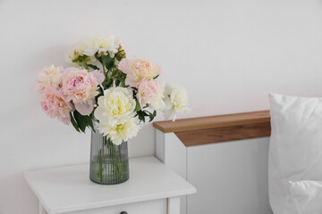 Vase with bouquet of beautiful peonies on bedside table, closeup