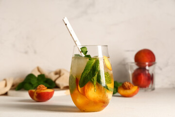Glass of fresh peach lemonade with mint on white background