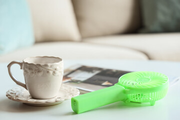 Small electric fan and cup on table in room