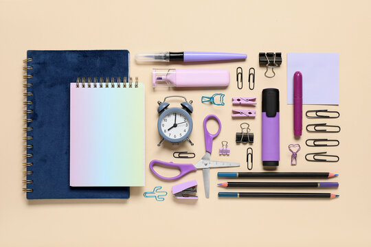 Different school stationery supplies and alarm clock on beige background - Powered by Adobe