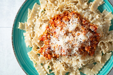 A top down view of a plate of gluten-free mafalde pasta, topped with dairy-free parmesan cheese.