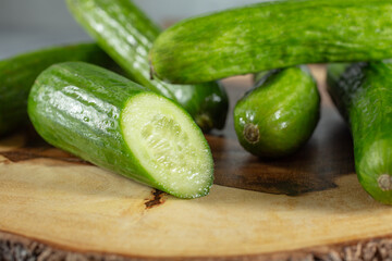 A view of pile of Persian cucumbers, on a wood board.