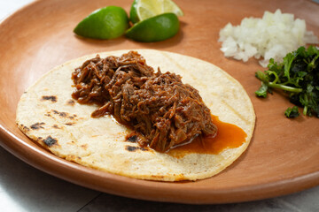 A closeup view of a beef birria taco, on a plate.