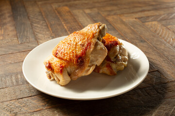 A view of two pan-fried chicken thighs, on a plate.