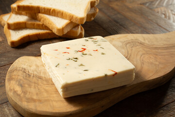 A view of a stack of dairy-free pepper jack cheese, on a wood board.