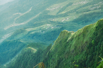 A scenic view of lush green mountains and valleys, with a distant village nestled among the trees.