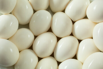 A top down view of a layer of peeled hard boiled eggs, as a background.