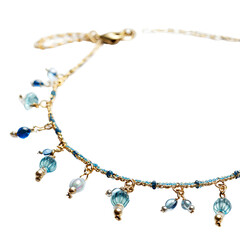 Delicate beaded necklace with light gold accents and varying shades of blue gemstones