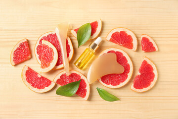 Grapefruit essential oil and massage tools on wooden background