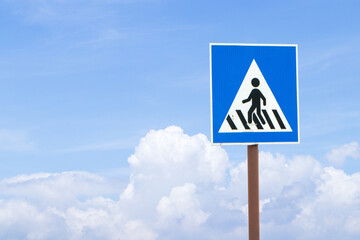 Blue, white pedestrian Zebra crossing sign square with blue sky cloud white is background. Signage warning traffic rules of people walking along city street to avoid moving car. Road safety concept.