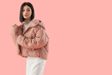 Young woman in stylish puffer jacket on pink background © Pixel-Shot