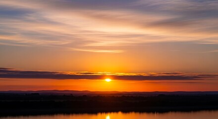 Naklejka premium Vibrant Orange Sunset Over a Calm Horizon.