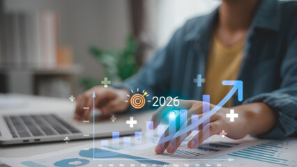 Hand pointing to a financial growth chart with upward trend and 2026 target icon. Concept for...