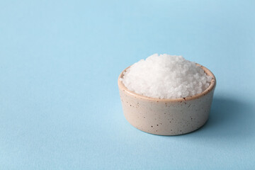 Ceramic bowl of sea salt on color background