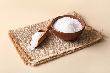 Bowl and scoop with sea salt on color background