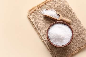 Bowl and scoop with sea salt on color background