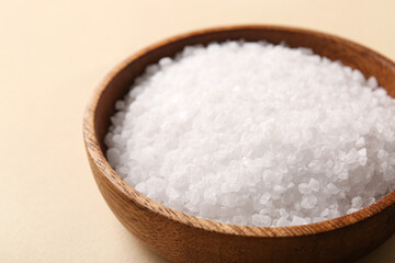 Wooden bowl of sea salt on color background, closeup