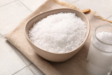 Bowl and jar with sea salt on light tile table