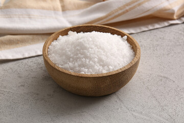 Wooden bowl with sea salt and napkin on grunge background
