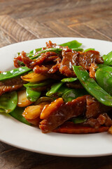A view of a plate of beef and snow peas.