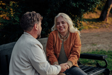 Happy senior couple holding hands and sharing a moment on park bench
