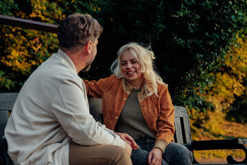 Senior couple enjoying conversation on park bench during autumn