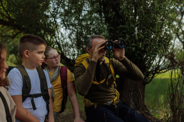 Teacher showing nature to students with binoculars during field trip