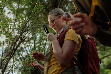Curious girl scout exploring nature with magnifying glass