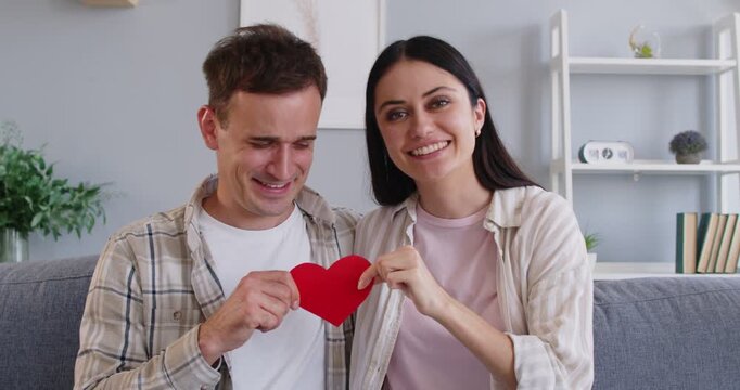 Happy funny couple, lovers express affection holding share red heart love valentine symbol, loving smiling male, female pair celebrate romantic love, friendship admiration, family enjoy St. Valentine
