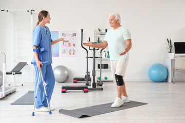 Senior man exercising without crutches and therapist in rehabilitation center
