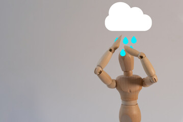 A wooden mannequin with its hands raised with a rainy cloud icon
