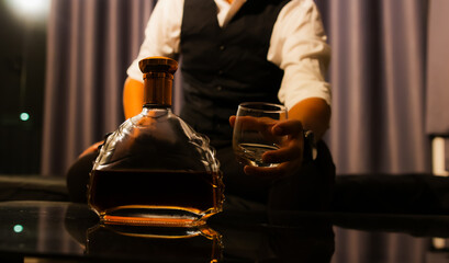 A highly experienced businessman in a tuxedo quietly pours whiskey in his home. A wealthy gentleman who exudes elegance, power and the contemplative luxury of nightlife.