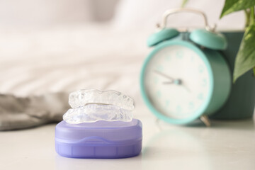 Box with occlusal splint on table in bedroom, closeup