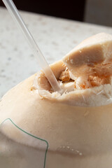 A closeup view of a young coconut with a plastic straw.
