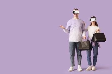 Young couple with VR glasses and shopping bags on lilac background. Cyber Monday