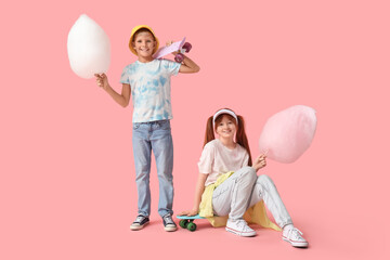 Teen girl and boy with cotton candy and skateboards on pink background